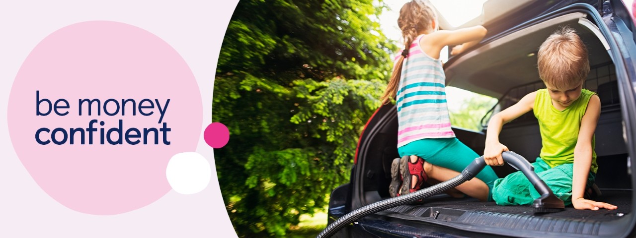 Two children cleaning and hoovering a car boot