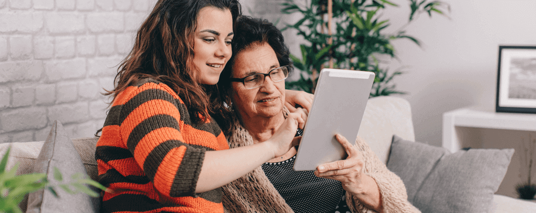 Two people sat on a sofa looking at a tablet