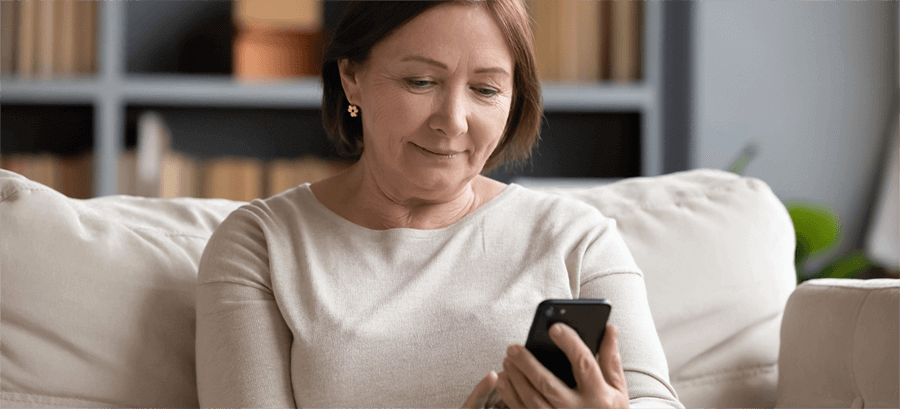 Woman sat on sofa using smartphone.